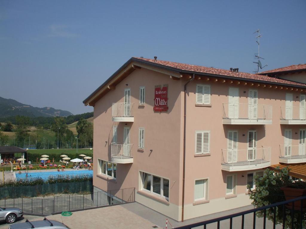 a large pink building with a pool in the background at Residence Hotel Matilde in Carpineti