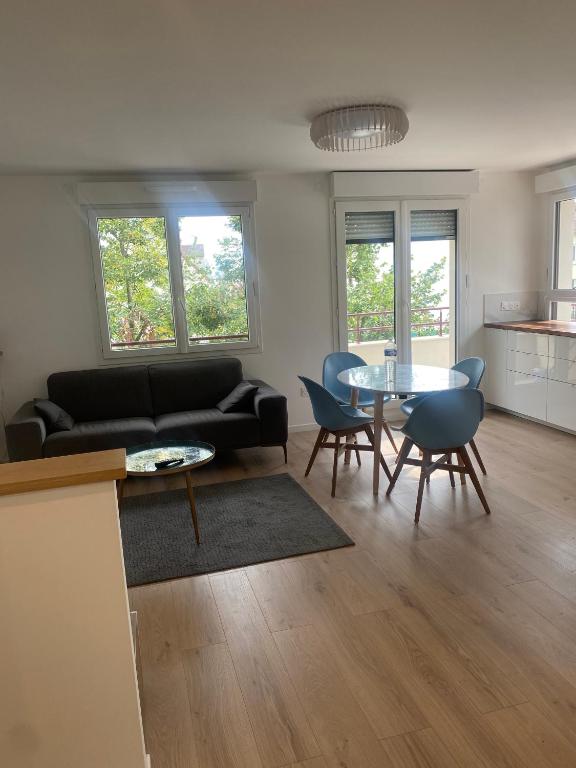 un salon avec un canapé noir et une table dans l'établissement AG Immobilier 95, à Bezons