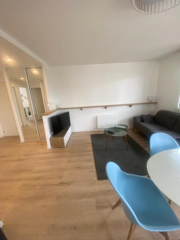 a living room with a couch and a table and chairs at AG Immobilier 95 in Bezons