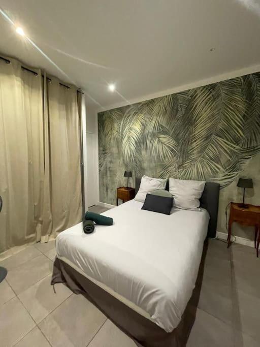 - une chambre dotée d'un grand lit blanc et d'une fresque murale dans l'établissement Jungle appart, à Nice