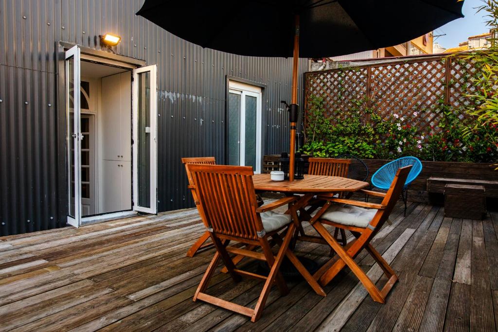een houten tafel en stoelen met een parasol op een terras bij Bonjardim Terrace in Porto