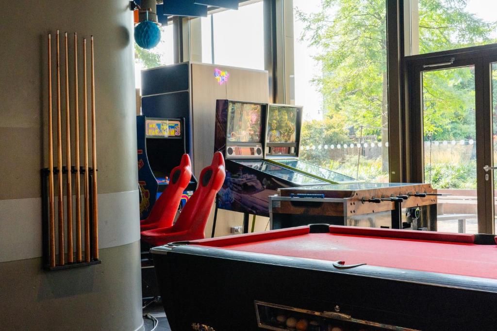 a room with a pool table and some red chairs at MEININGER Hotel Amsterdam City West in Amsterdam