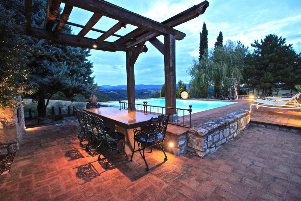 un patio con mesa y sillas junto a una piscina en Casa Boschetto, en San Venanzo