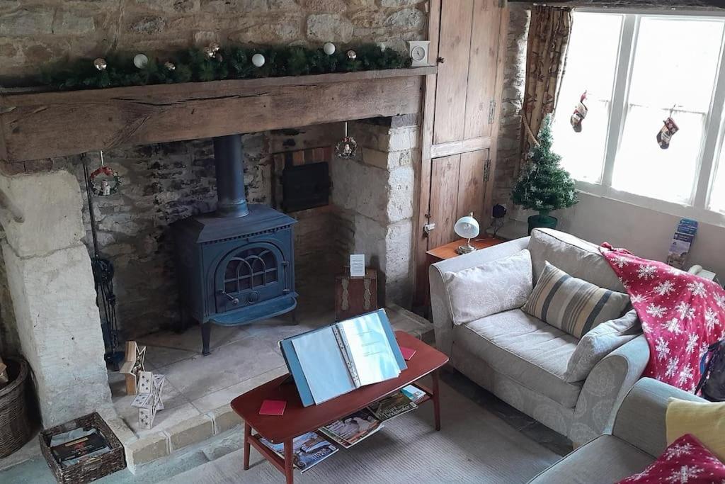 a living room with a couch and a fireplace at Well Cottage in Beckington