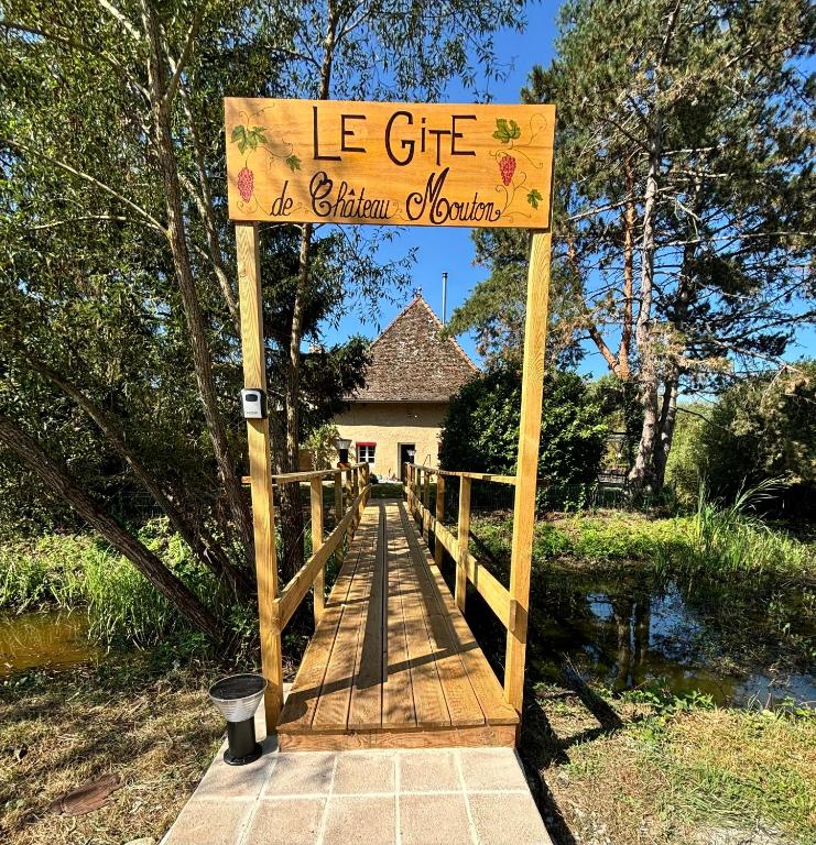 un pont en bois avec un panneau devant une maison dans l'établissement Le gîte du Château Mouton, à Châtenoy-le-Royal