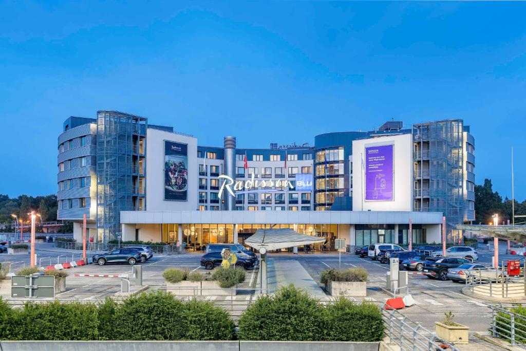 a large building with cars parked in a parking lot at Radisson Blu Hotel, Hamburg Airport in Hamburg