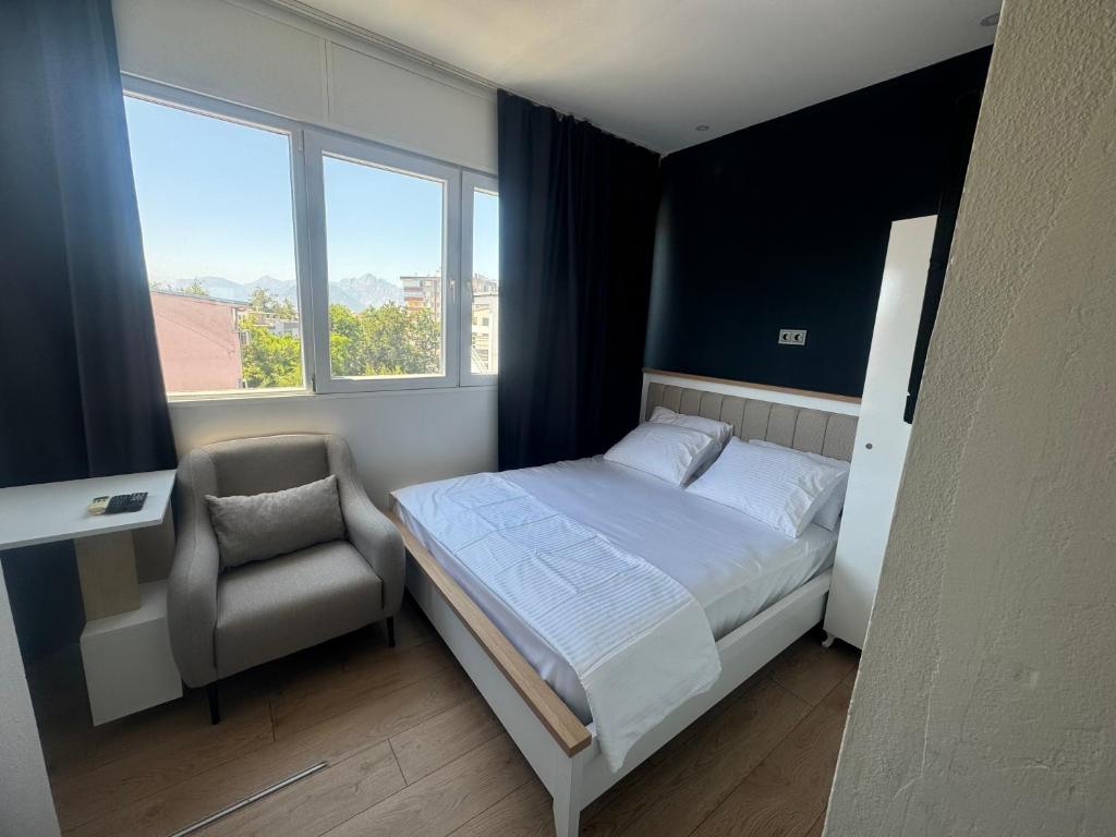 een slaapkamer met een bed, een stoel en ramen bij Turap Homes in Antalya