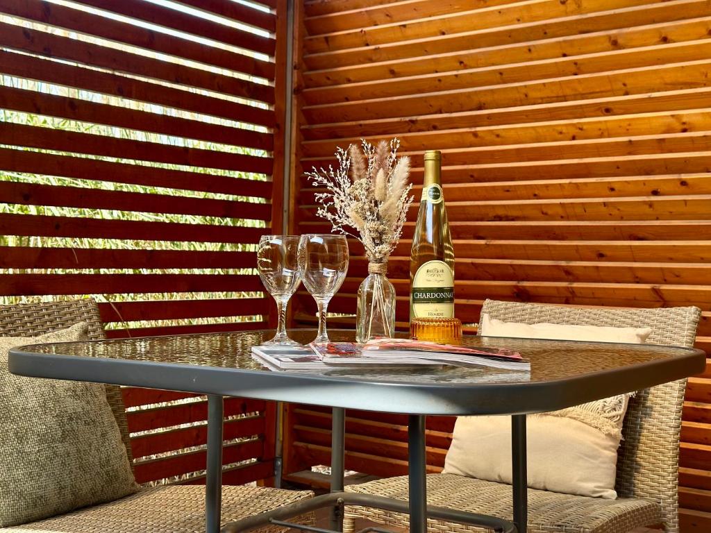 Glass-topped table with wine bottle, two wine glasses and dried-flower arrangement, relaxed patio setting.