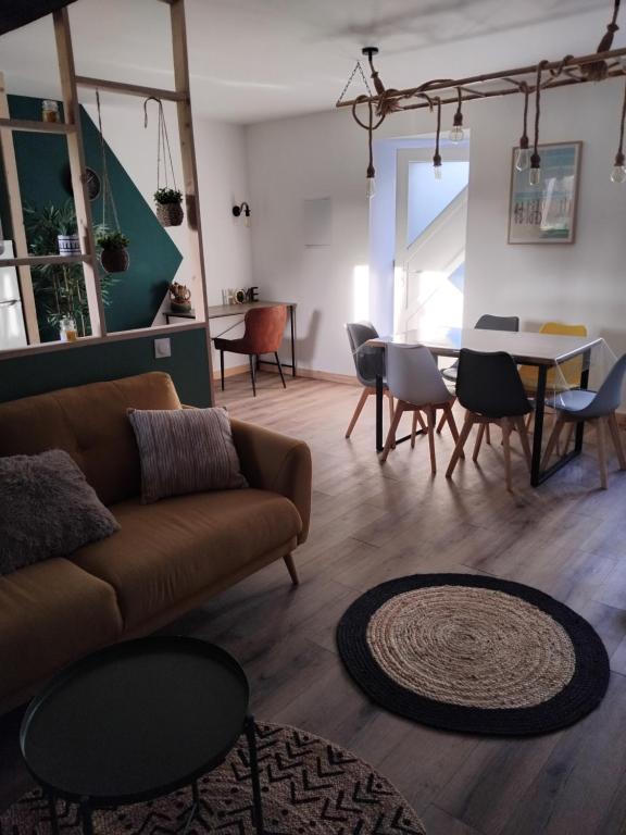 a living room with a couch and a table and chairs at La grange aux animaux in Tollevast