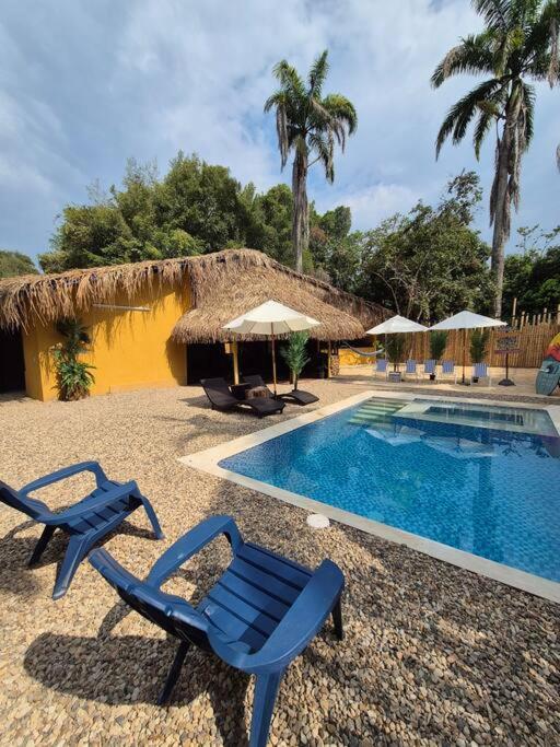 Ecoluxury Villa Yakarta Playa artificial minicine في ميلغار: وجود زوج من الكراسي الزرقاء جالسه بجانب مسبح