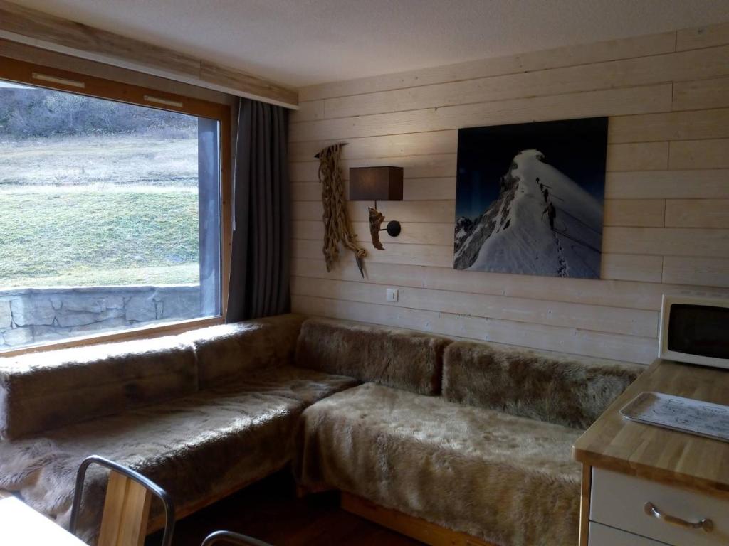 un canapé en cuir dans une pièce avec une fenêtre dans l'établissement Appartement Méribel au pied des pistes avec balcon, casier à skis et WIFI - FR-1-355-29, à Méribel