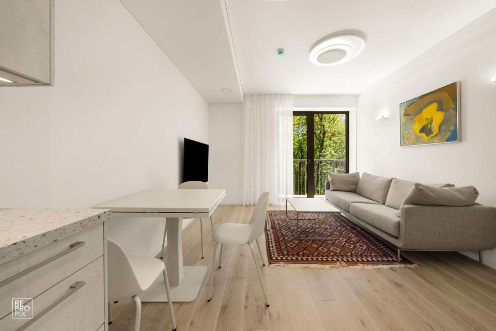 a white living room with a couch and a table at Bright 2BR with Private EV Parking, workspace, AC in Kaunas