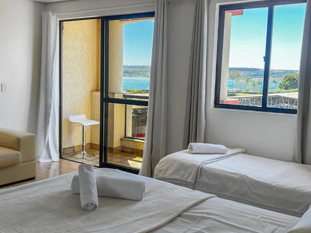 a bedroom with two beds and a large window at Lake Side Resort Flat Beira Lago 5 minutos do centro de Brasília in Brasília