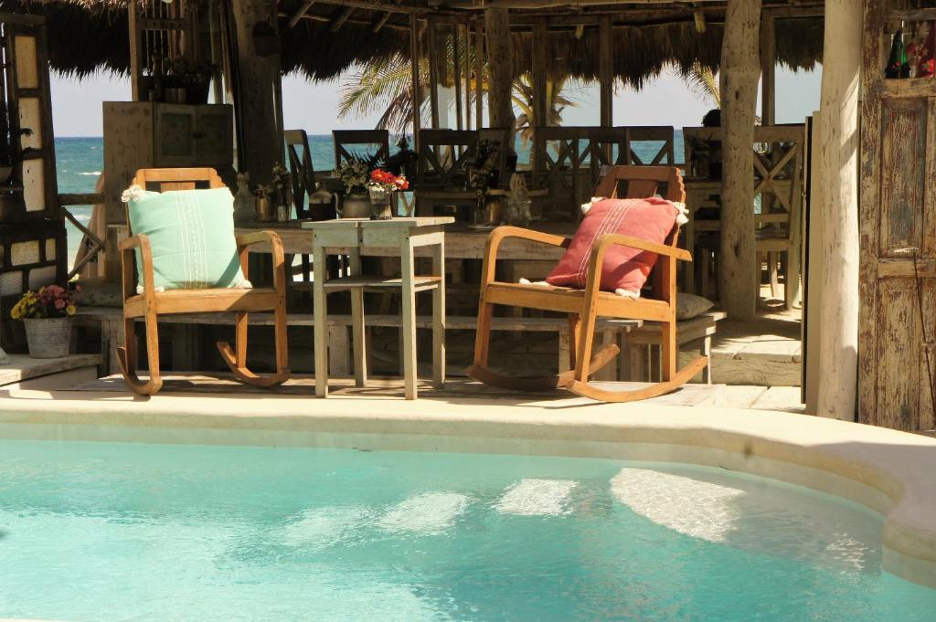 two chairs and a table next to a swimming pool at Punta Piedra Beach Posada in Tulum