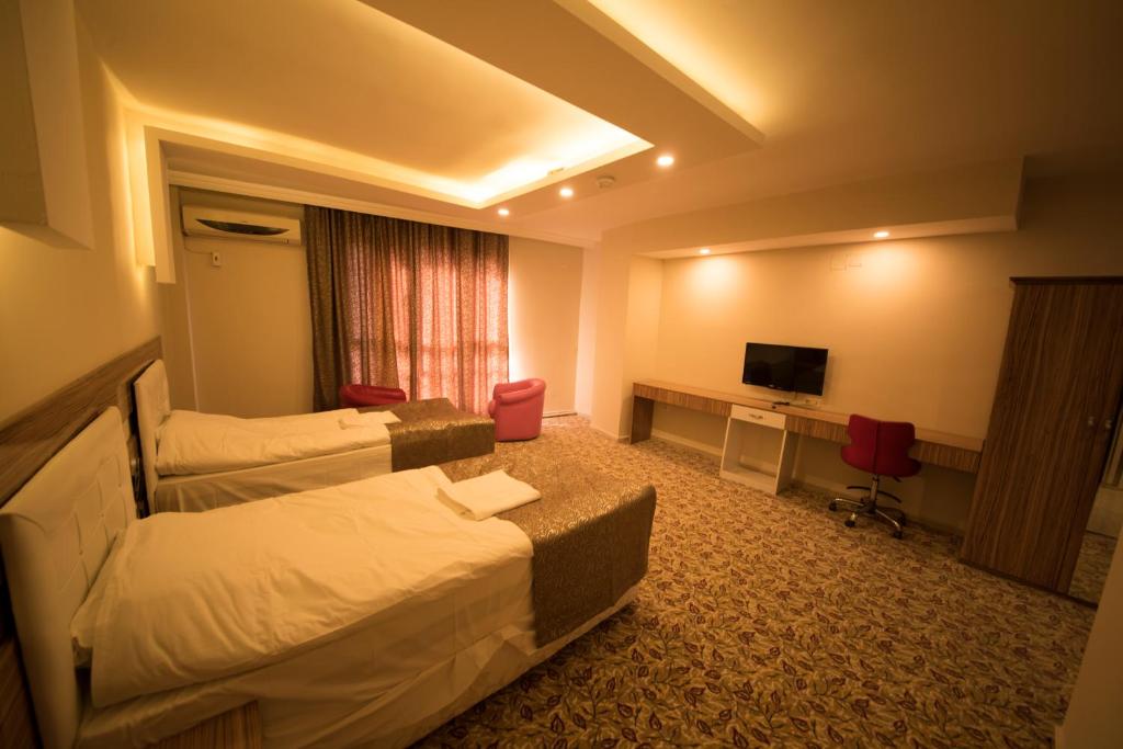a hotel room with two beds and a television at Osmaniye Hanedan Otel in Osmaniye