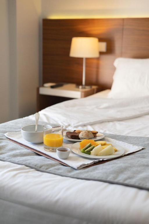 uma bandeja de comida de pequeno-almoço numa cama em Hotel Navarras em Amarante