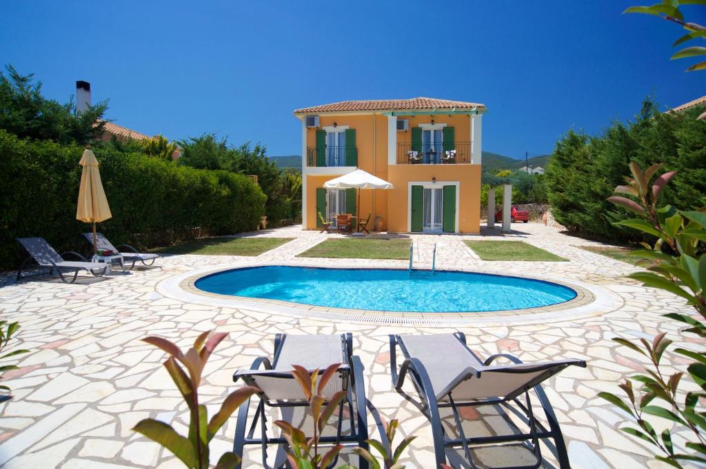 a villa with a swimming pool in front of a house at Iliachtides Villas in Karavomylos