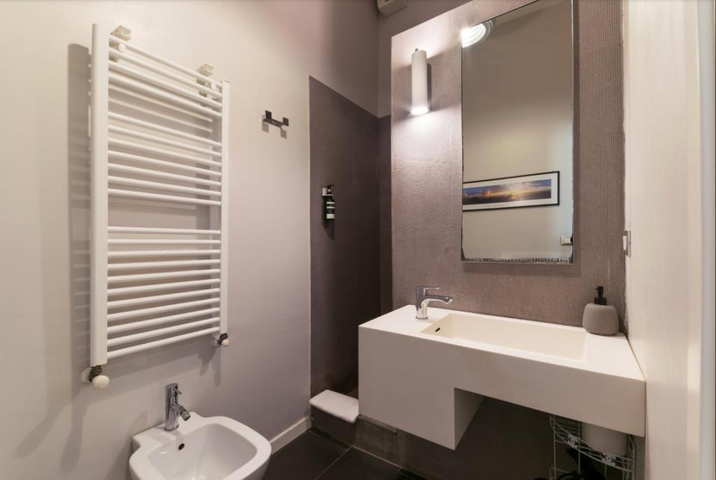 łazienka z umywalką, toaletą i lustrem w obiekcie B&B Parigi w Bolonii