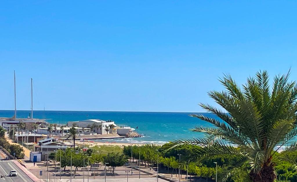 a view of a beach with a palm tree and the ocean at Apartment Vicente in Vilanova i la Geltrú
