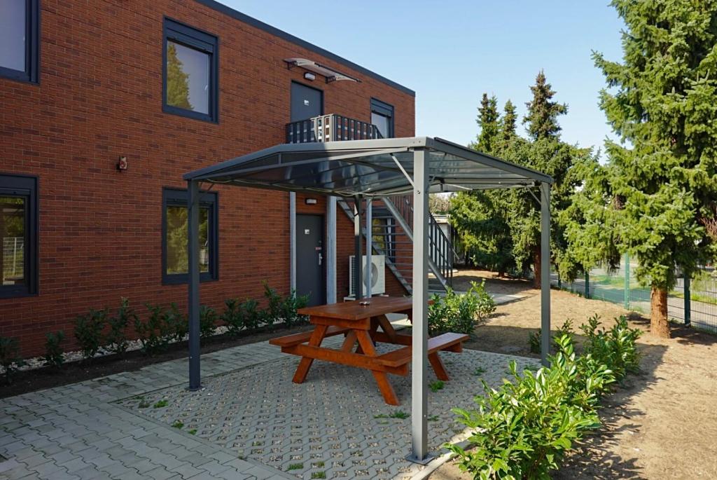 einem Picknicktisch unter einem Baldachin vor einem Gebäude in der Unterkunft Comfort Housing Apartments in Falkensee