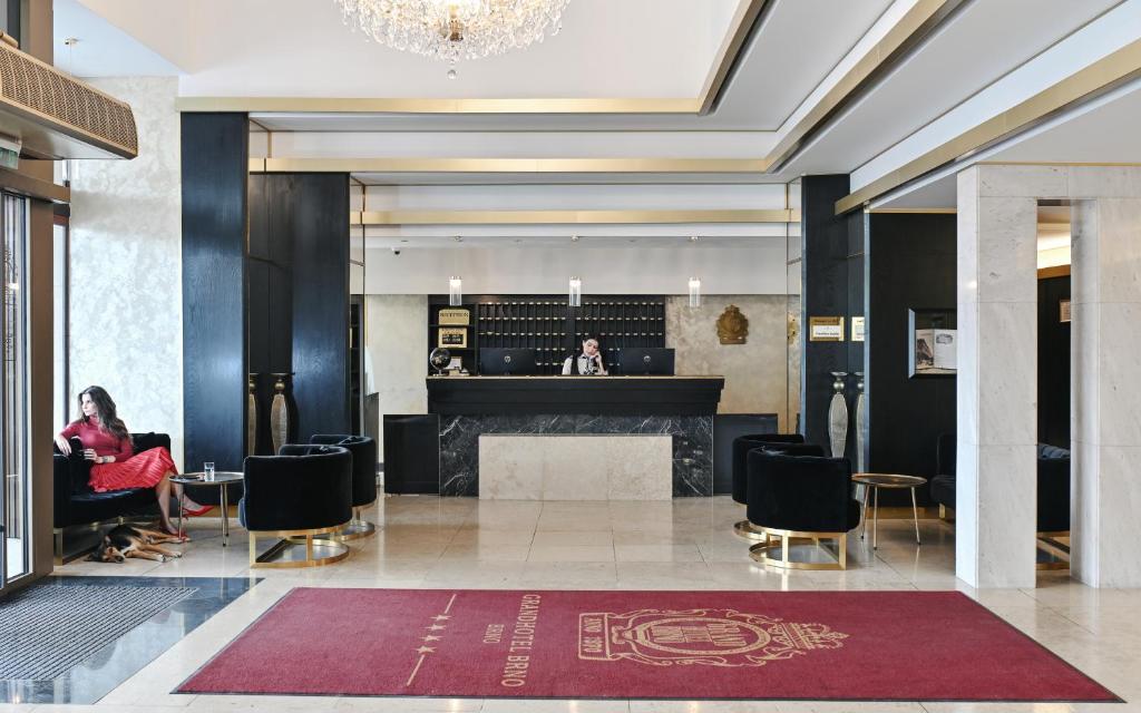 a lobby of a hotel with a woman sitting in a chair at Grandhotel Brno in Brno