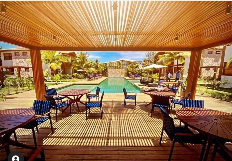 un patio con tavoli, sedie e piscina di Lindo Villaggio em Barra Grande a Barra Grande