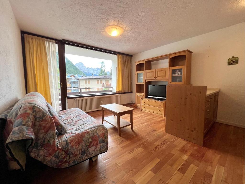 un salon avec un canapé et une grande fenêtre dans l'établissement Bilocale Slalom, à Madonna di Campiglio