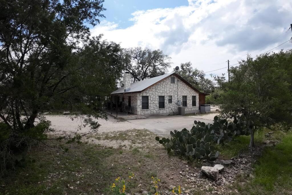 un ancien bâtiment blanc dans un champ arboré dans l'établissement Laurel Canyon - Frio River Haven, à Concan