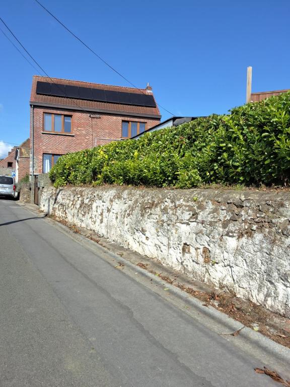 a stone wall next to a street with a building at Le petit nid in Brugelette