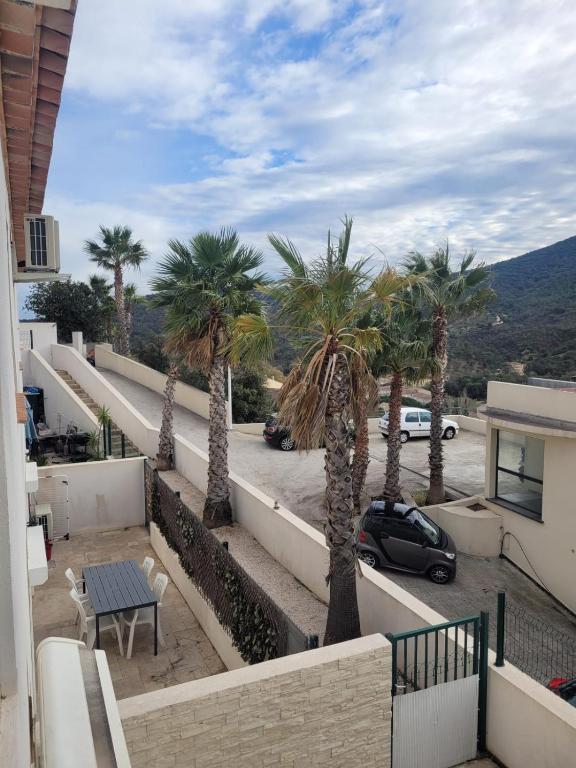 - un balcon avec des palmiers dans un parking dans l'établissement Appartement neuf avec terrasse plein sud à Sainte-Maxime, à Sainte-Maxime