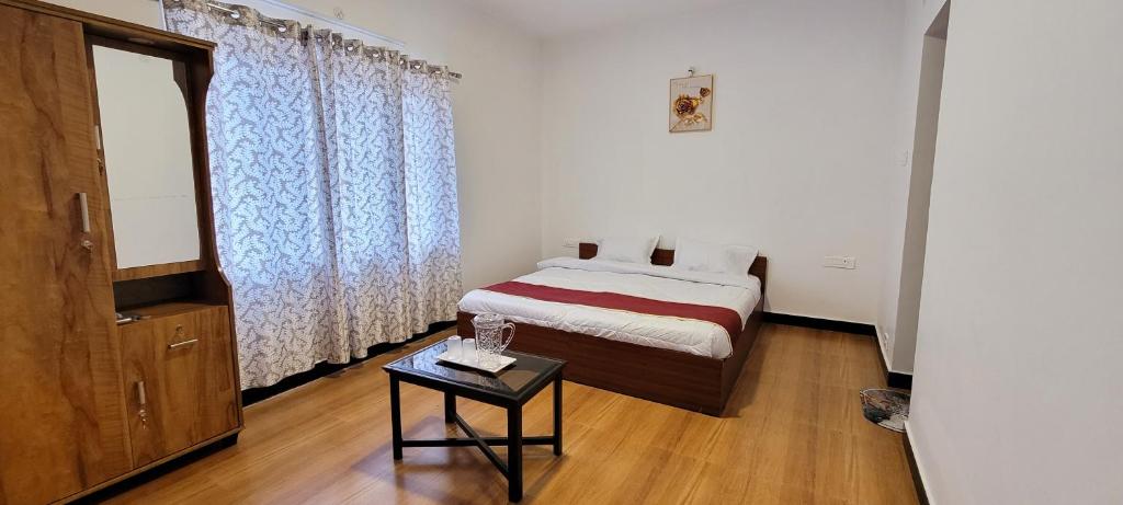 a small bedroom with a bed and a table in it at AJ Groups B&B Residency in Ooty