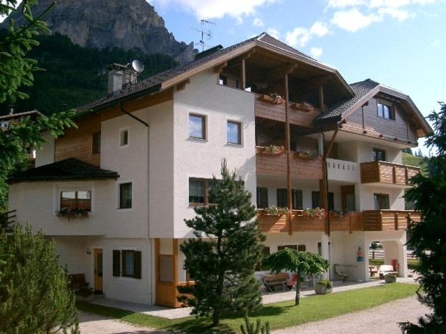 a large white building with a mountain in the background at Residence Majarai in Colfosco