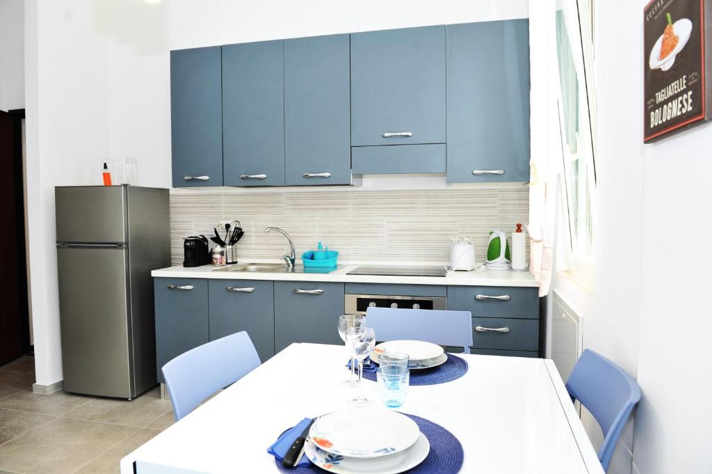 een keuken met blauwe kasten en een witte tafel en stoelen bij La Dimora In Blu in Bologna