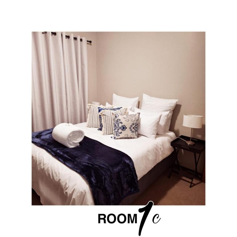 a bedroom with a bed with pillows and curtains at The Cottage in Cradock