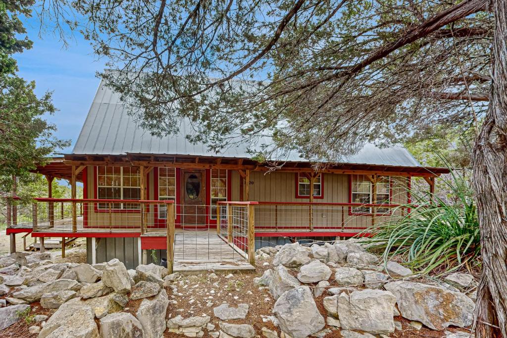 a red house with a porch and a stone wall at Driftwood Hideaway in Canyon Lake