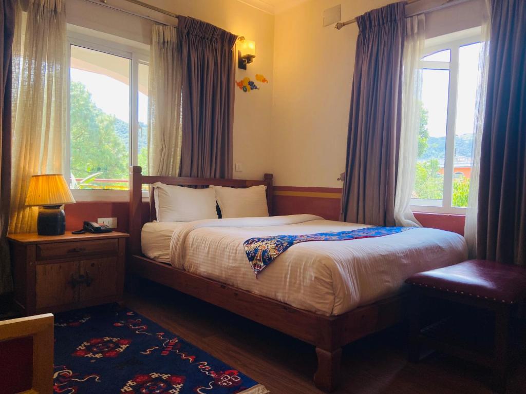 ポカラにあるThree Jewels Boutique Hotelのベッドと大きな窓のある寝室