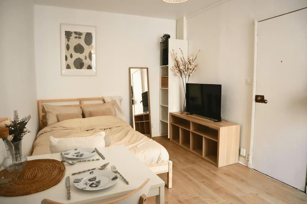 une chambre avec un lit, une table et une télévision dans l'établissement Cocon Moderne à Nation, Paris, à Paris