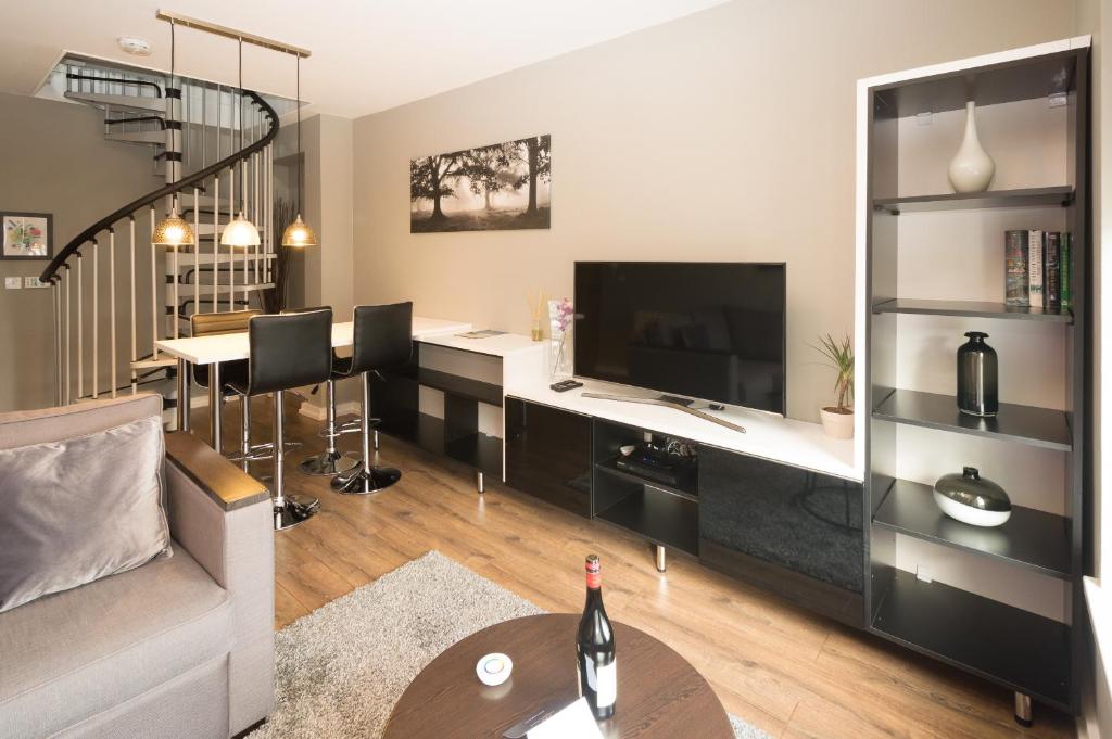 a living room with a couch and a desk with a television at Aaron Wise Apartments in Cardiff