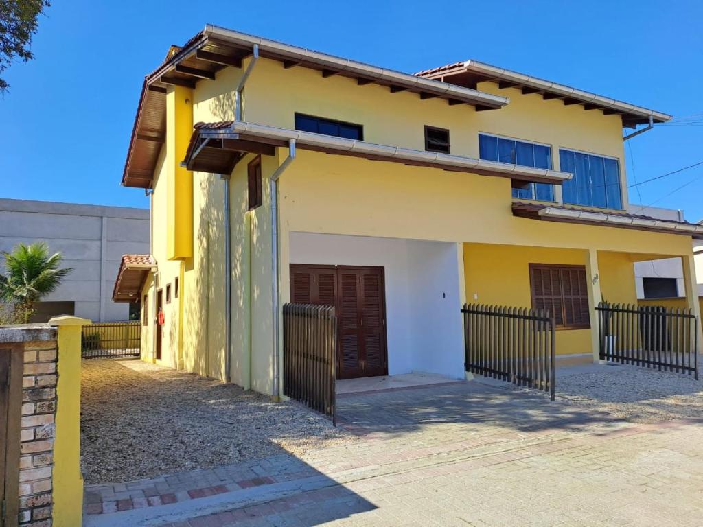 a yellow house with a gate in front of it at Brusque Comfort Studios in Brusque