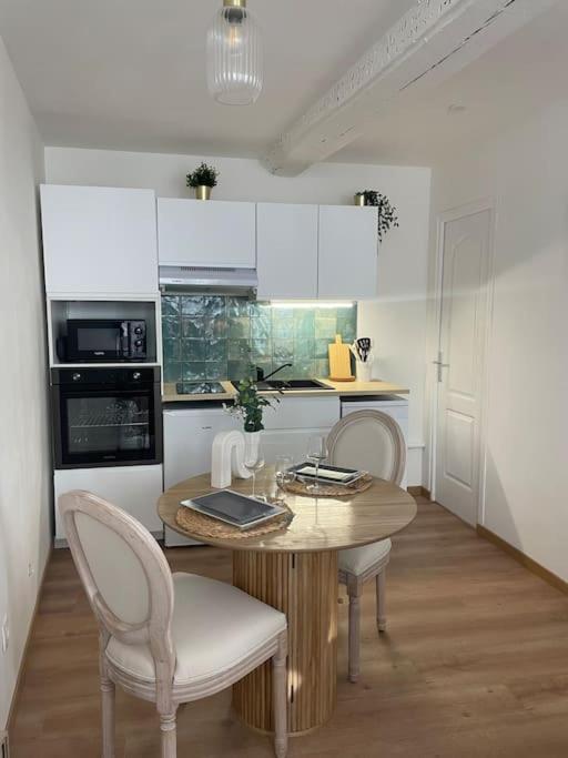 une cuisine avec une table et deux chaises et une cuisine avec des placards blancs dans l'établissement Au coeur de la baie, à Saint-Valery-sur-Somme