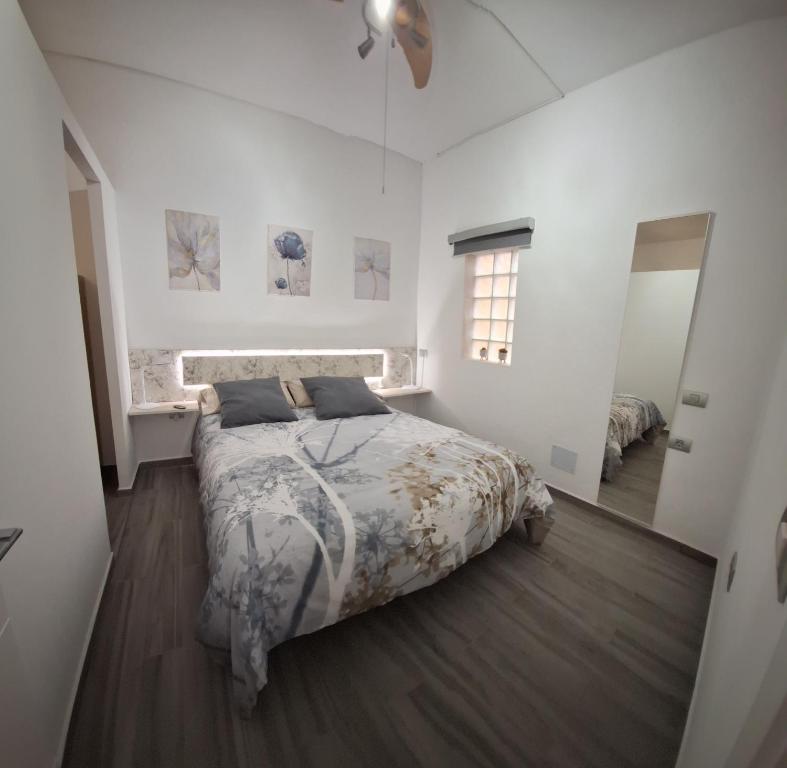 a white bedroom with a bed and a mirror at Casita Leos in Agüimes