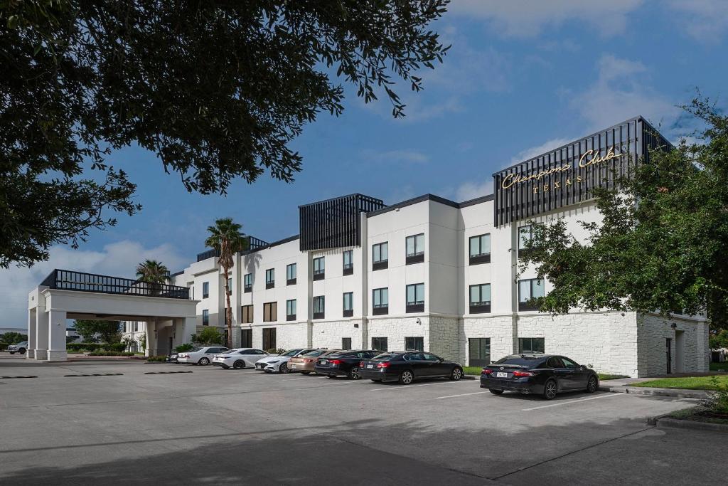 a large white building with cars parked in a parking lot at Champions Club and Hotel, Houston Westchase in Houston