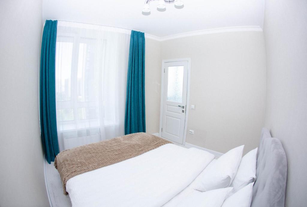 1 dormitorio con 1 cama con cortinas azules y ventana en Slavutich apartment #2, en Kiev