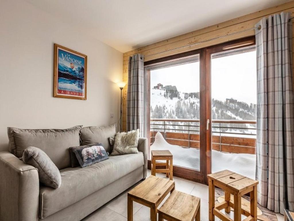 un salon avec un canapé et une grande fenêtre dans l'établissement Résidence Lodges 1970 - Résidence LES LODGES1970 N° A507 MAE-5041, à La Plagne Tarentaise