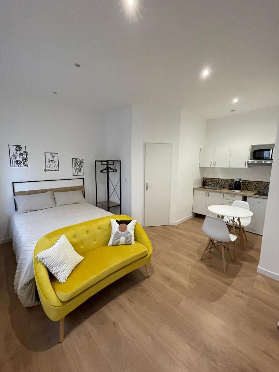 - une chambre avec un lit et un canapé jaune dans l'établissement Edenly Stay, à Saint-Quentin