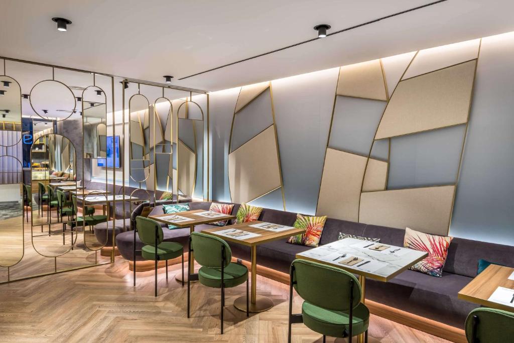a dining room with tables and green chairs at Occidental Alicante in Alicante
