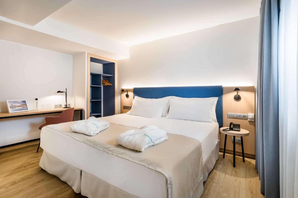 a bedroom with a large bed with two towels on it at Occidental Alicante in Alicante