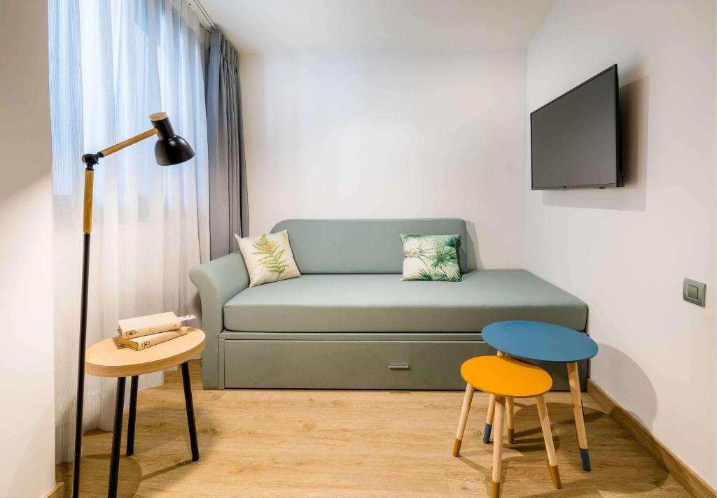 a living room with a couch and a table and stool at Occidental Alicante in Alicante