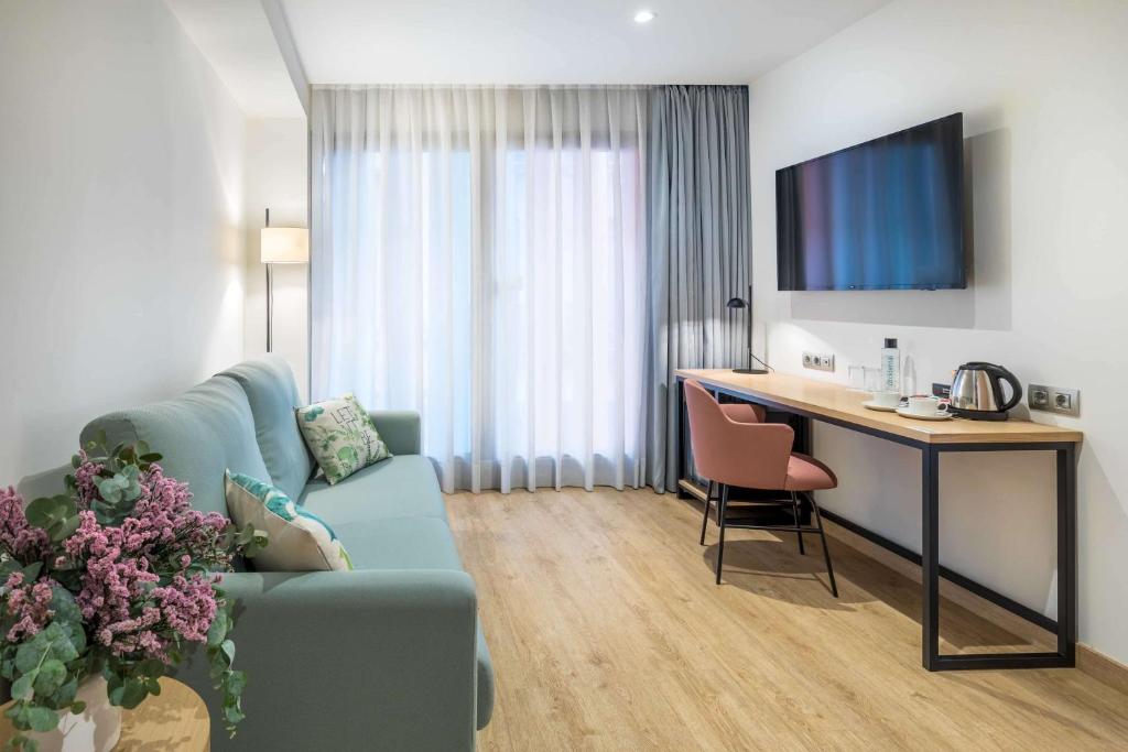 a living room with a blue couch and a desk at Occidental Alicante in Alicante