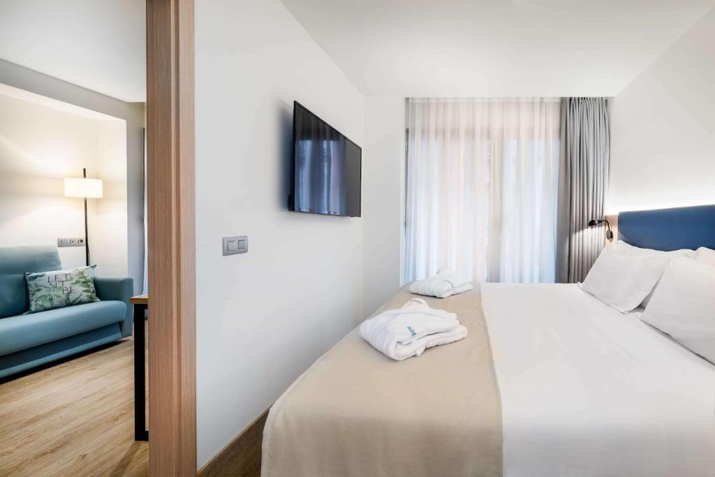 a hotel room with a bed and a blue couch at Occidental Alicante in Alicante